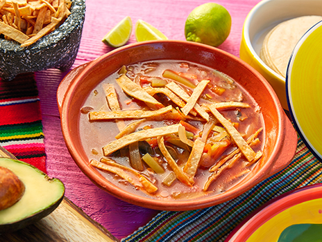 Bowl of enchilada soup with tortilla strips on top.