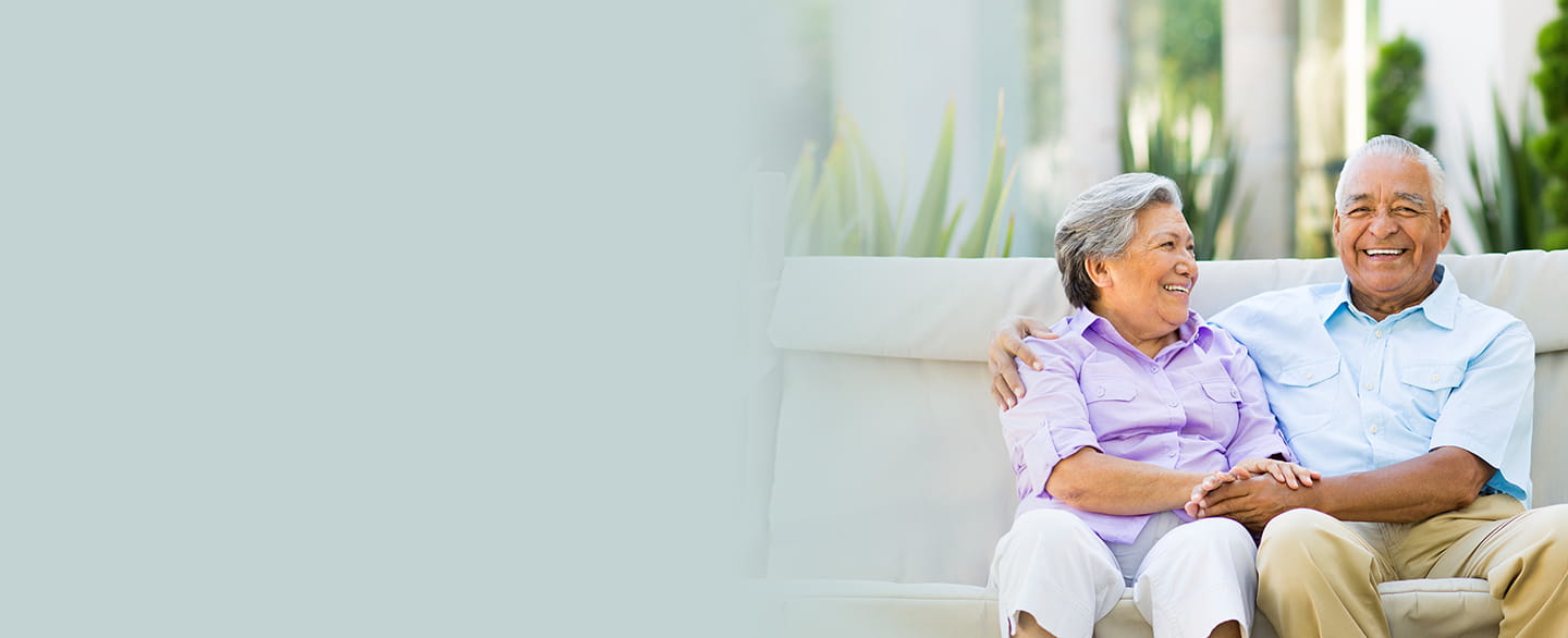 Older couple sitting outside smiling.
