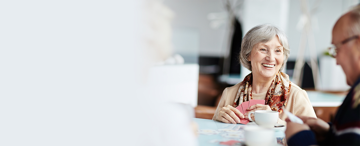 Older woman playing cards with friends. 