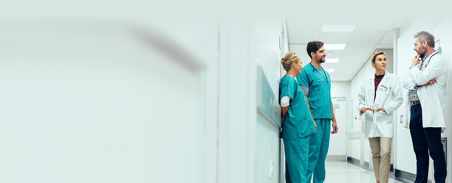 Nurses and doctors talking in hospital hallway.