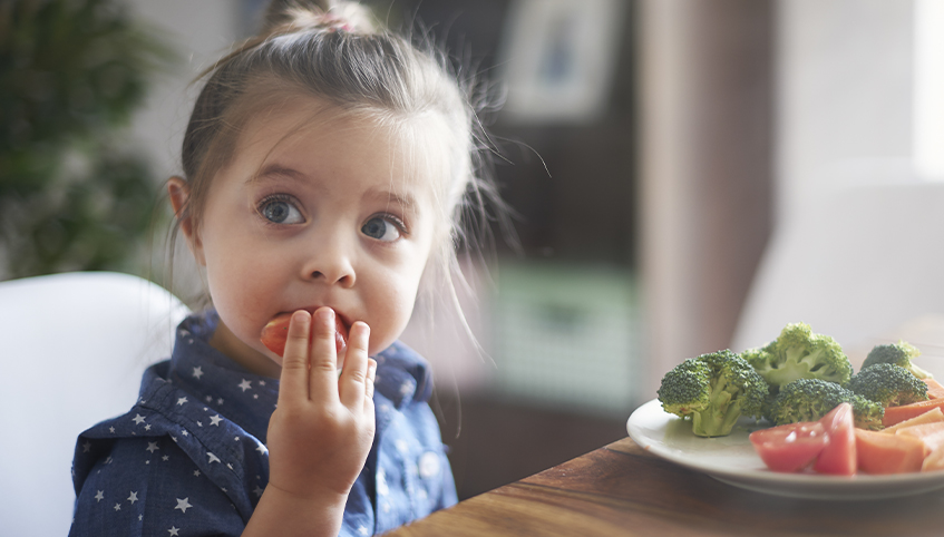 Little girl eating her vegetables.