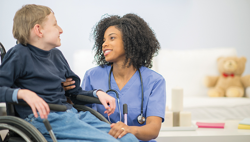Nurse talking with young patient in wheelchair.