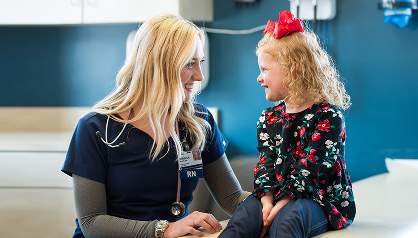 Pediatric nurse talking with little girl.