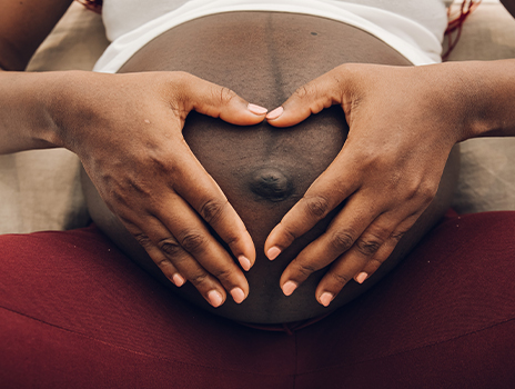 Pregnant black woman making a heart over her belly