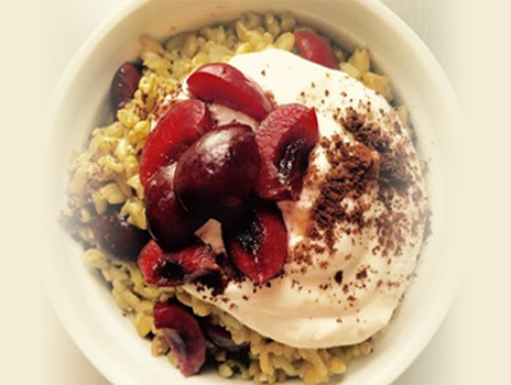 Freekeh bowl topped with cherries and greek yogurt.
