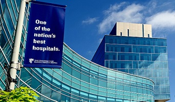 A banner hangs from a streetlight pole in front of a pedestrian bridge. The banner reads "One of the nation's best hospitals."