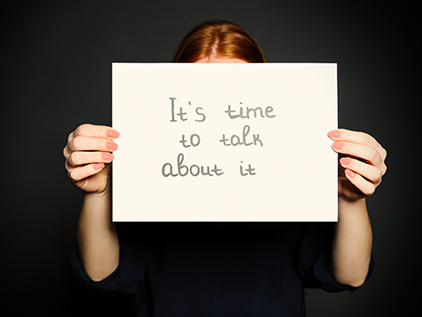 Person holding sign saying, "It's time to talk about it"