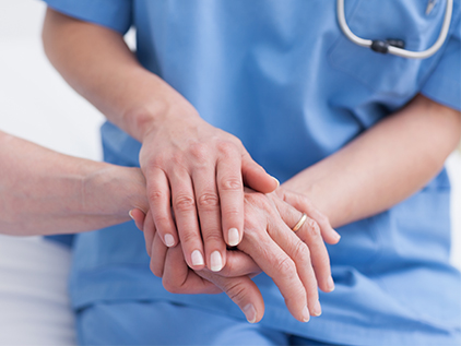 Nurse holding patient's hand to comfort them. 