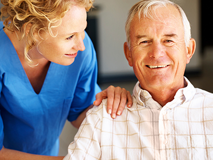 Nurse with her hand on a smiling patient's shoulder.