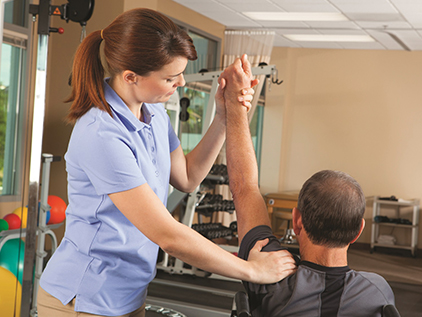 Provider stretching man's shoulder in physical therapy. 