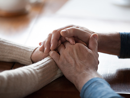 People holding hands to comfort one another.