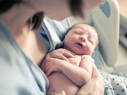 Mother holding newborn in hospital bed