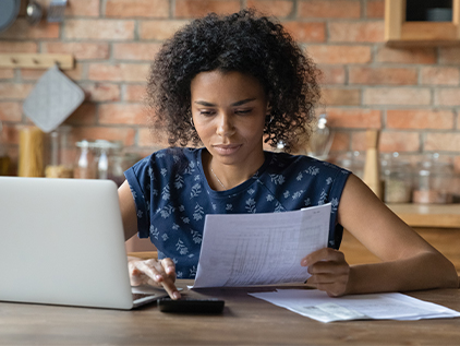 Woman looking at bills in front of her computer