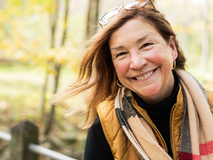 Woman outside during the fall season, smiling at the camera