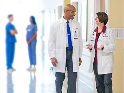 Two doctors talking in hospital hallway.