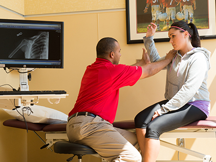 Sports medicine nurse examining patient's shoulder.