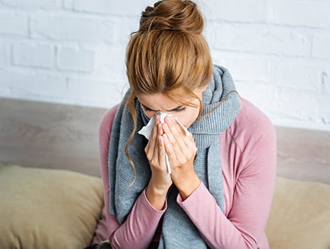 Woman sneezing in tissue