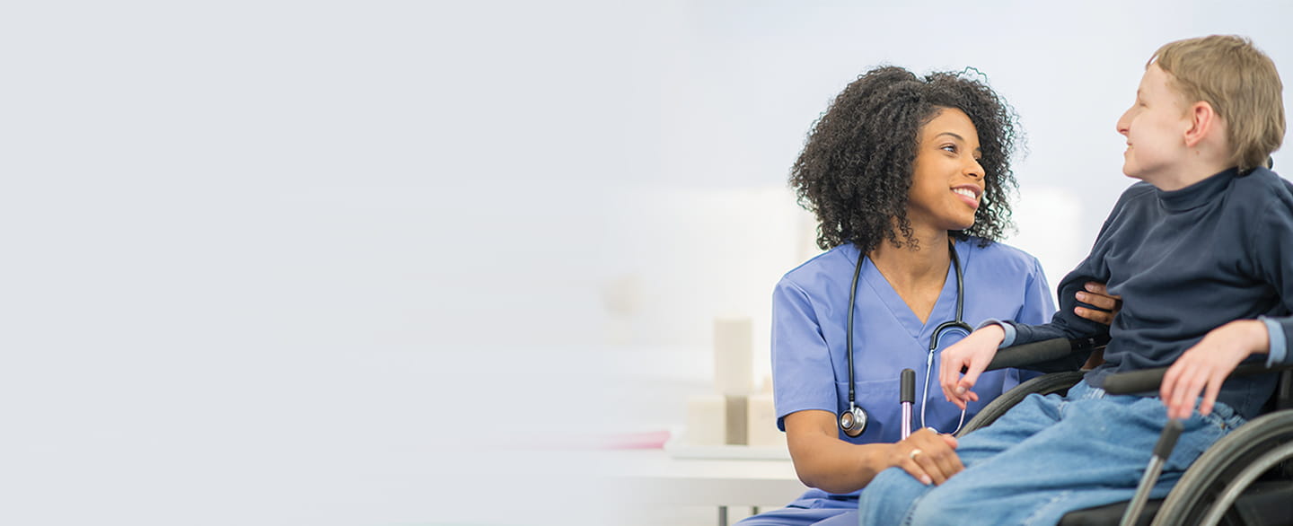 Nurse talking with young patient in wheelchair.