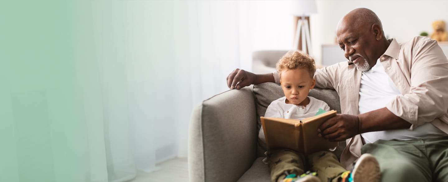grandfather sitting and reading with toddler