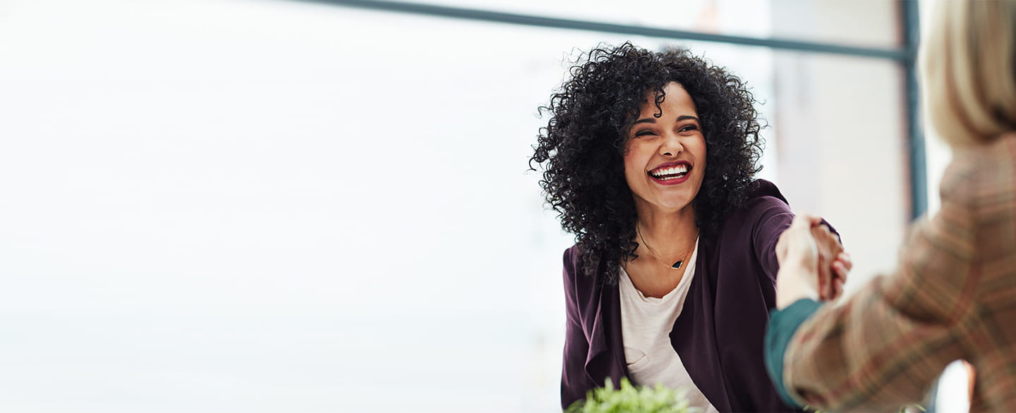 Woman shaking hands and smiling.