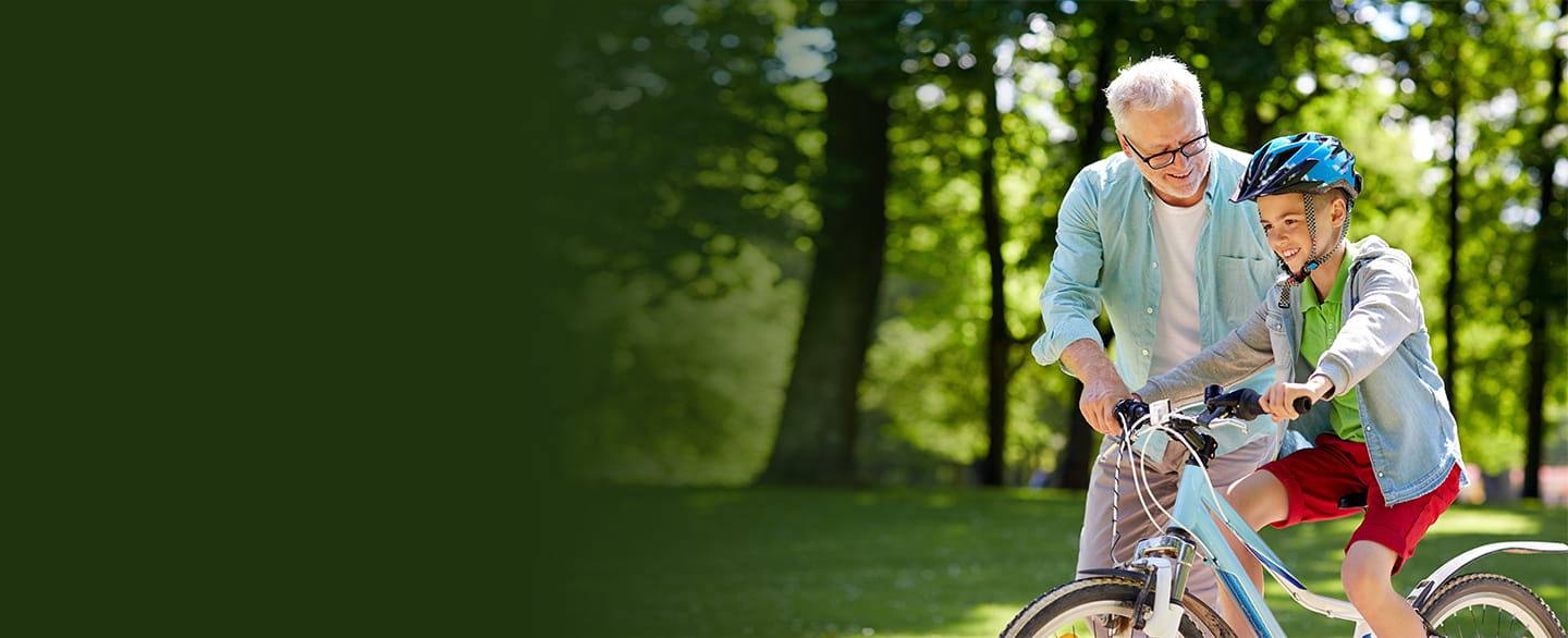 Grandpa helping grandson on bike.