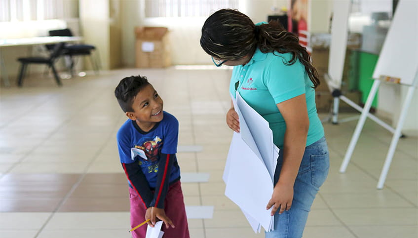 Young boy smiling at his teacher.