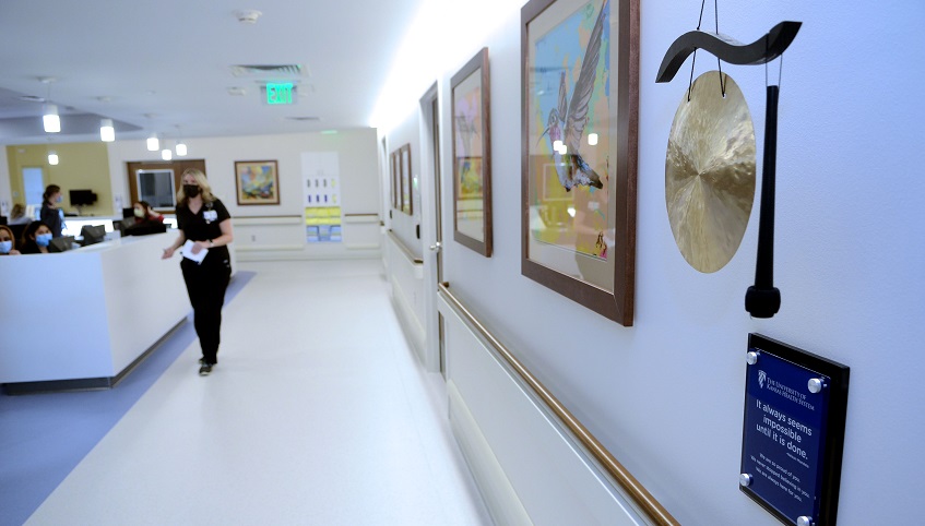 A gong and mallet hangs at the end of a hospital hallway.