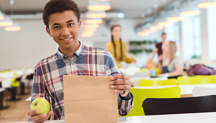 Kid with a bagged lunch at school