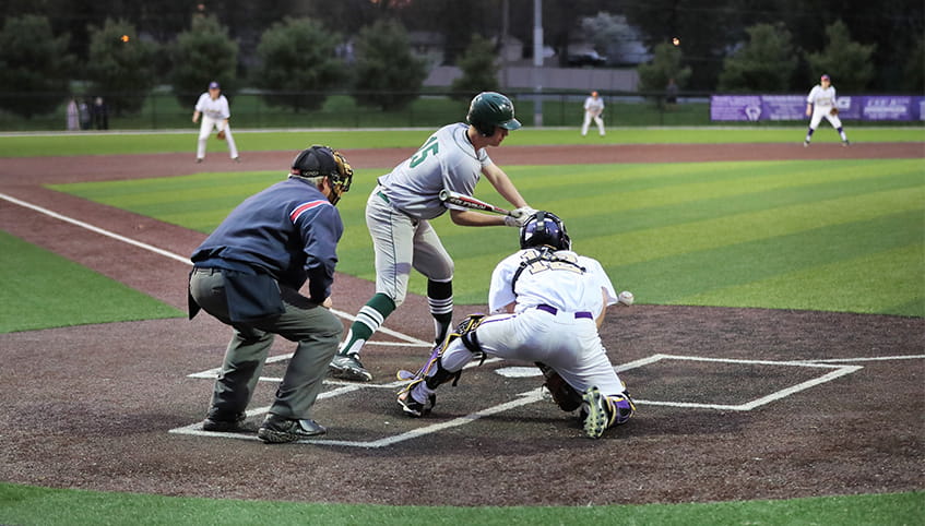 Player swinging at baseball during a game.