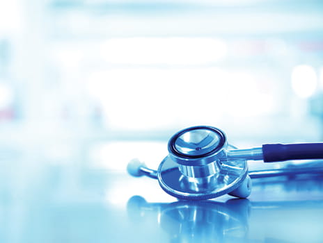 Stethoscope laying on a table against a blurred clinical background
