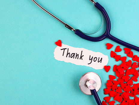 Handwritten thank you with a stethoscope and paper hearts