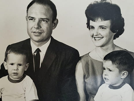 Black and white posed photo of Toby Cook's family. Pictured are Toby, his father, mother and sibling.