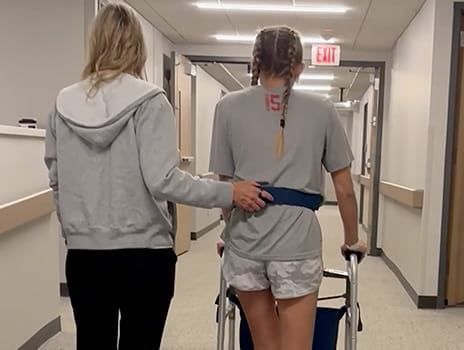 Kendall being assisted walking down hospital hall