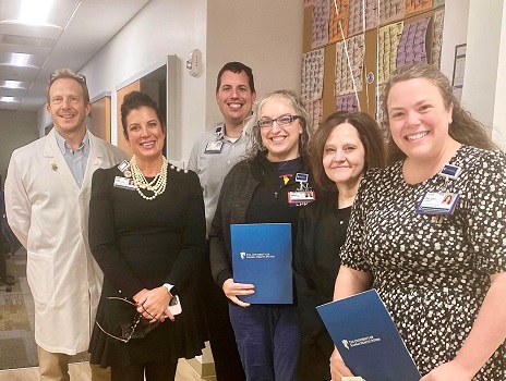 Marcia Petty, wearing glasses and holding a blue folder, stands with members of nursing leadership and infectious disease to celebrate her RFTS scholarship.