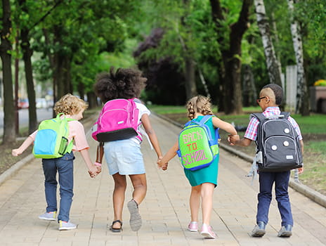 Kids with backpacks holding hands