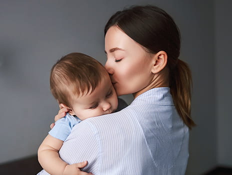 Mother holding and kissing a baby