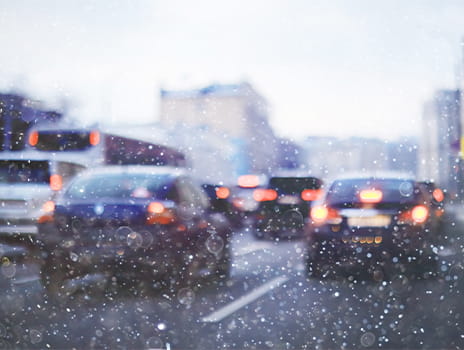 Looking out of a windshield, in traffic, during a snow storm