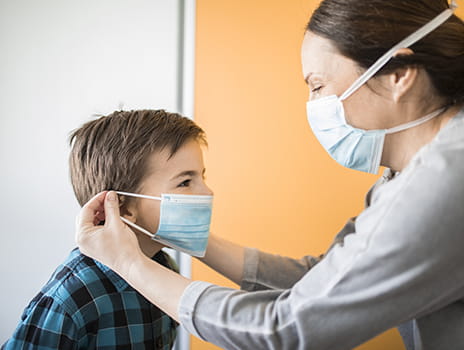 Mom helping put mask on child.