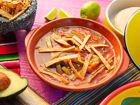 Bowl of enchilada soup with tortilla strips on top.