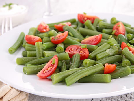 Plate of green beans with tomatoes.