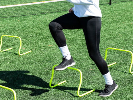 Female athlete running over mini hurdles