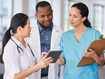 three doctors looking at a tablet