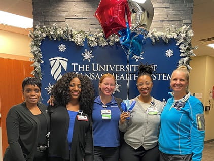 Lauren McNeely holds balloons as she stands with nursing leaders celebrating her RFTS scholarship