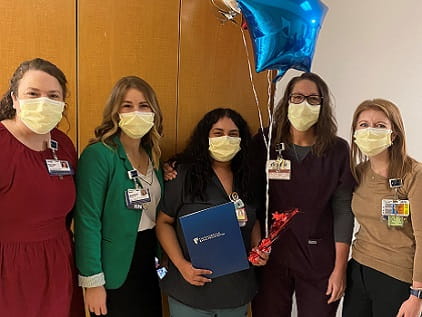 Melanie Melendez Garcia holds balloons and stands with members of nursing leadership to celebrate her RFTS scholarship