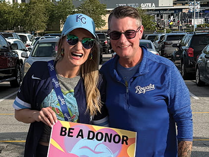 Marina Tosi smiling holding a be a donor sign