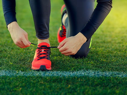 Teen athlete tying shoes on field