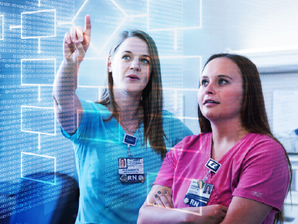 Two nurses looking at data on screen.